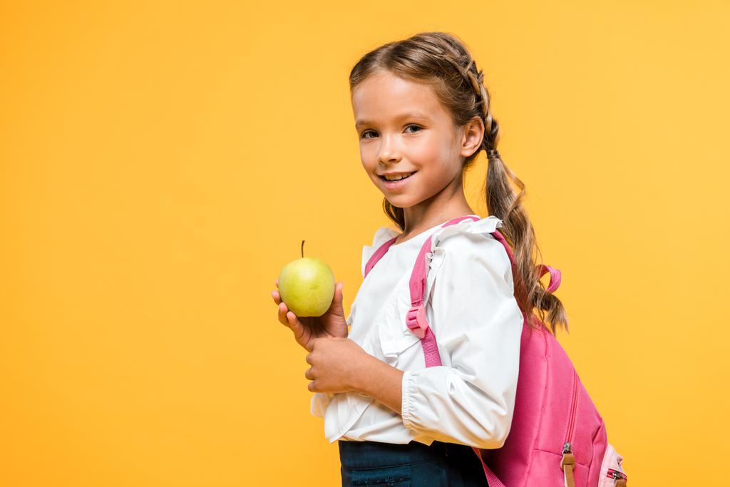 happy schoolchild holding tasty apple isolated on orange  - Photo, Image