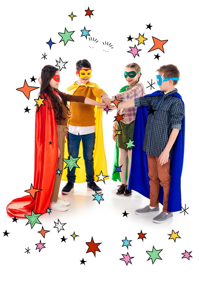 szczęśliwe dzieci w SuperHero kostiumy i maski układania rąk w pobliżu gwiazd na białym  - Zdjęcie, obraz
