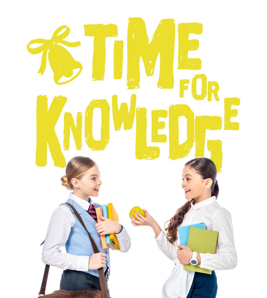Schulmädchen in offizieller Kleidung mit Büchern und Apfel in der Nähe Zeit für Wissensbuchstaben auf weiß  - Foto, Bild
