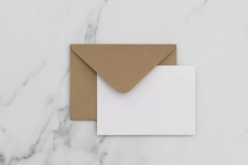 大理石のバックグにクラフト茶色の紙の封筒が付いている空白の白いカード - 写真・画像