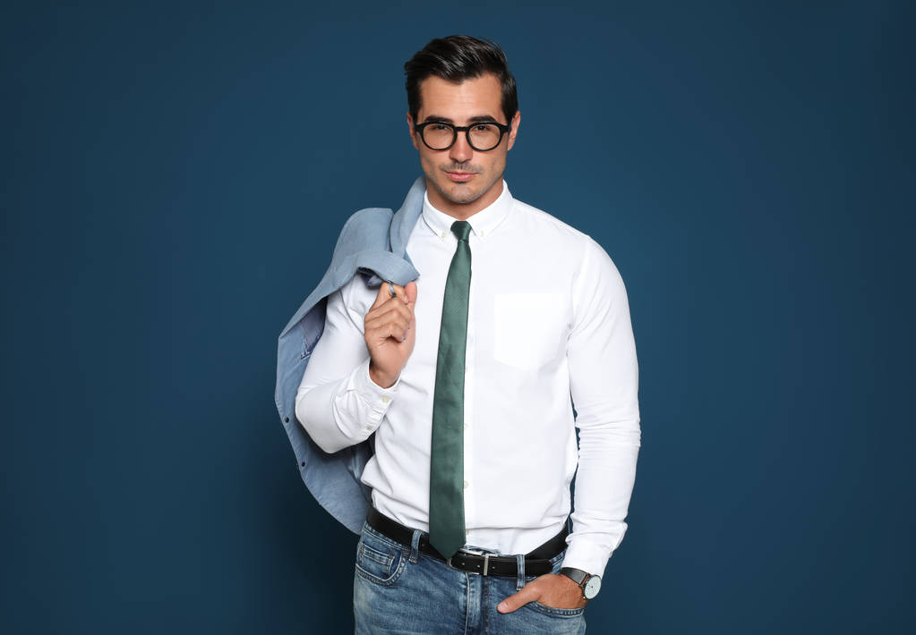 Πορτρέτο του όμορφου νεαρού επιχειρηματία φορώντας γυαλιά σε μπλε φόντο - Φωτογραφία, εικόνα