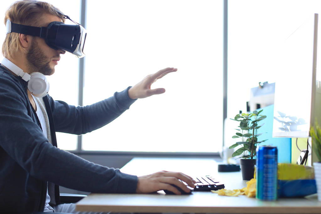 Jonge man met baard draagt een virtual reality bril in een modern interieurontwerp coworking studio. - Foto, afbeelding