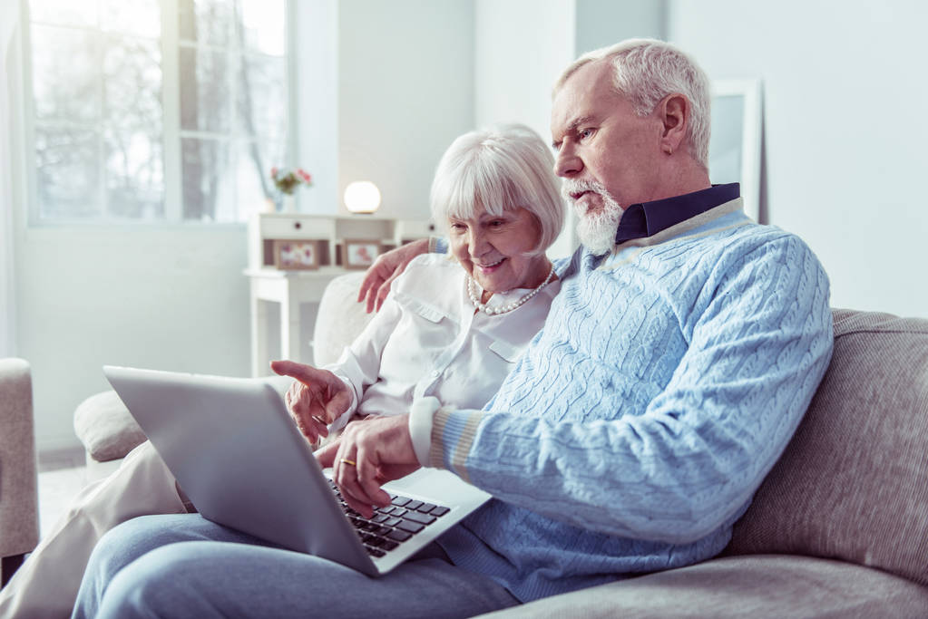 Пара сучасних бабусь і дідусів дивляться на ноутбук під час відеочату
 - Фото, зображення