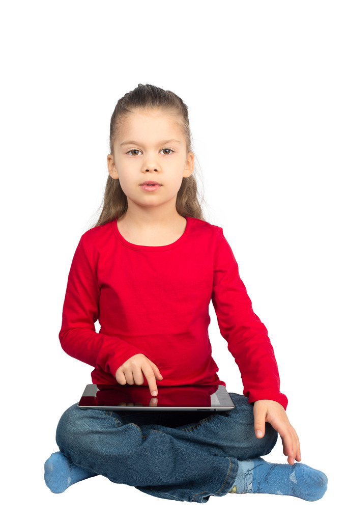 Маленька дівчинка з планшетним комп'ютером сидить з ногами схрещеними
 - Фото, зображення