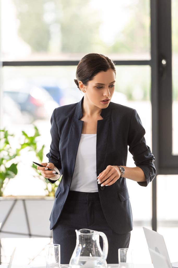 attractive businesswoman in formal wear holding pen in office - Photo, Image