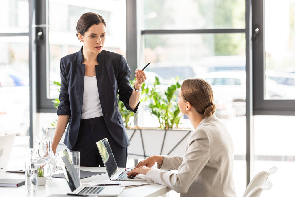 twee zakenvrouwen in formele slijtage kijken naar elkaar en praten in Office - Foto, afbeelding