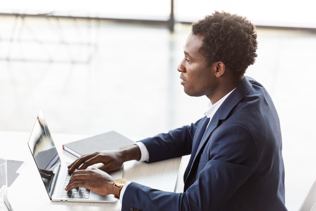 pensoso uomo d'affari afroamericano digitando sulla tastiera del computer portatile in ufficio
 - Foto, immagini