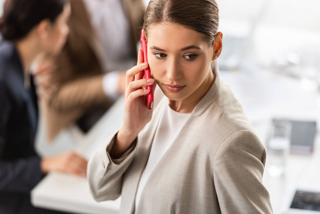 Nachdenkliche Geschäftsfrau in offizieller Kleidung spricht im Büro auf dem Smartphone - Foto, Bild