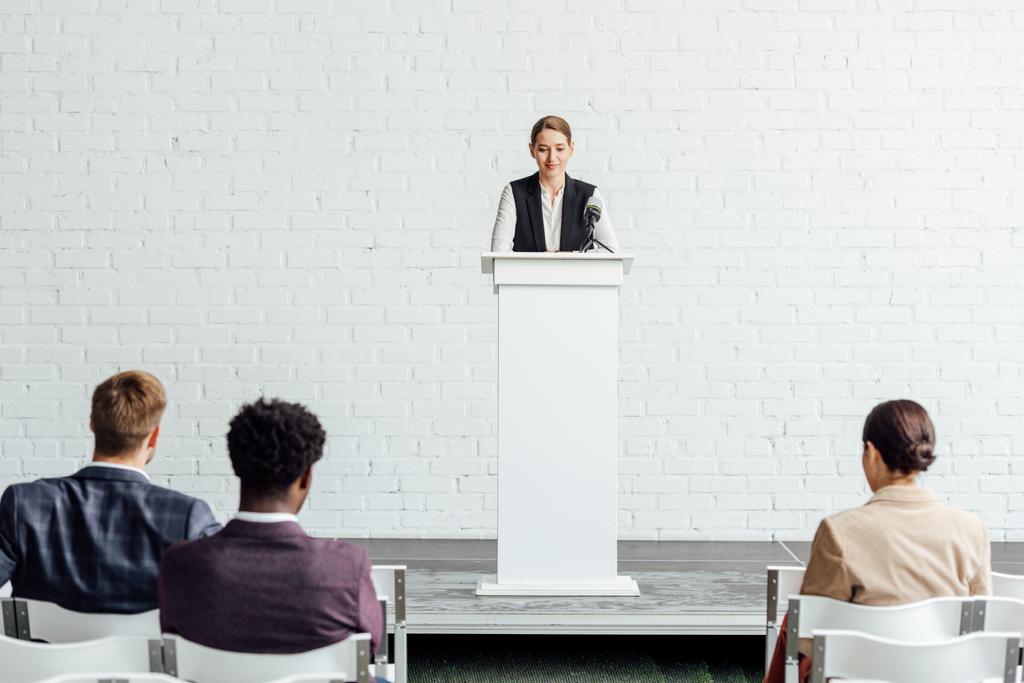 atraente empresária de pé e falando durante conferência na sala de conferências
 - Foto, Imagem