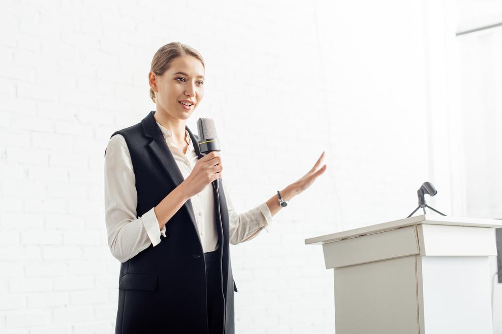 attraktive Geschäftsfrau hält Mikrofon in der Hand und spricht während der Konferenz im Konferenzsaal - Foto, Bild