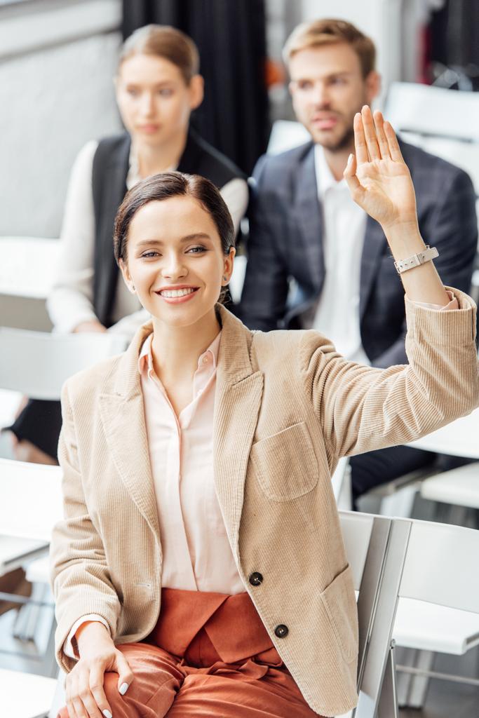 selective focus of attractive woman in formal wear raising hand during conference  - Photo, Image