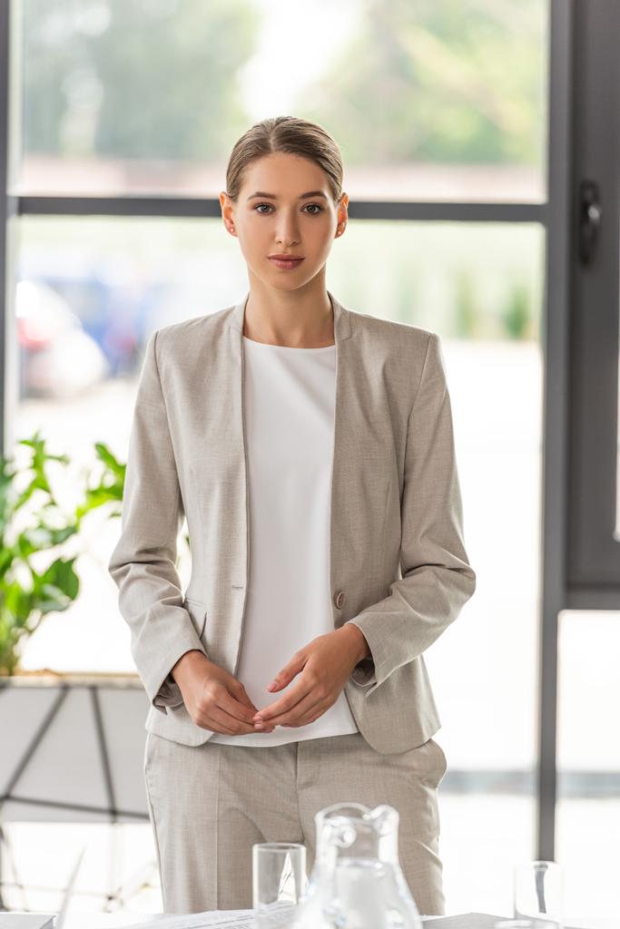 attraktive Geschäftsfrau in formeller Kleidung blickt im Büro in die Kamera  - Foto, Bild