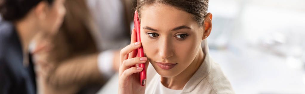 Panoramaaufnahme einer attraktiven Geschäftsfrau, die mit dem Smartphone spricht und wegschaut  - Foto, Bild