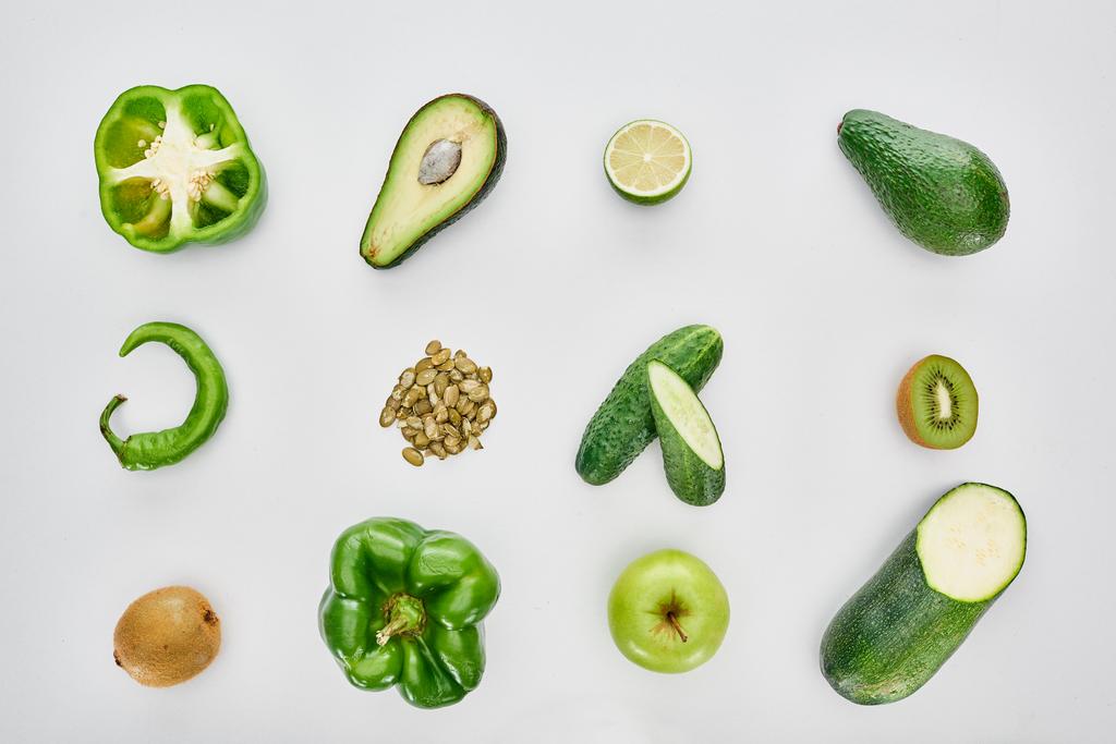 Top uitzicht van appel, avocado's, komkommers, limoen, paprika, pompoenpitten en courgette - Foto, afbeelding