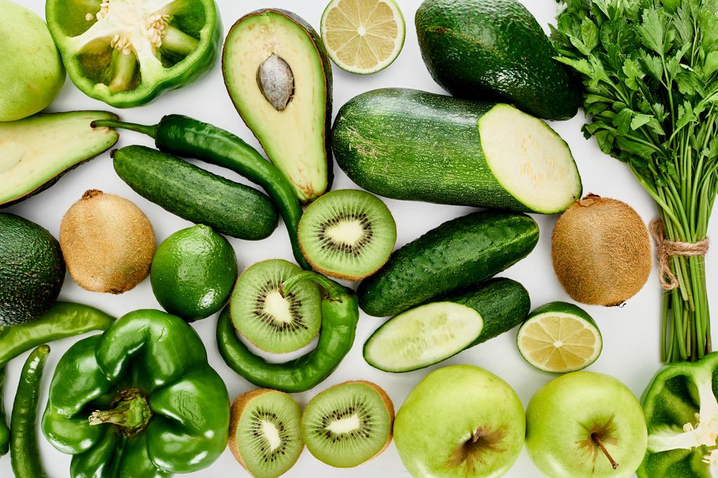 Draufsicht auf Äpfel, Avocados, Gurken, Limetten, Paprika, Kiwi, Grün und Zucchini - Foto, Bild