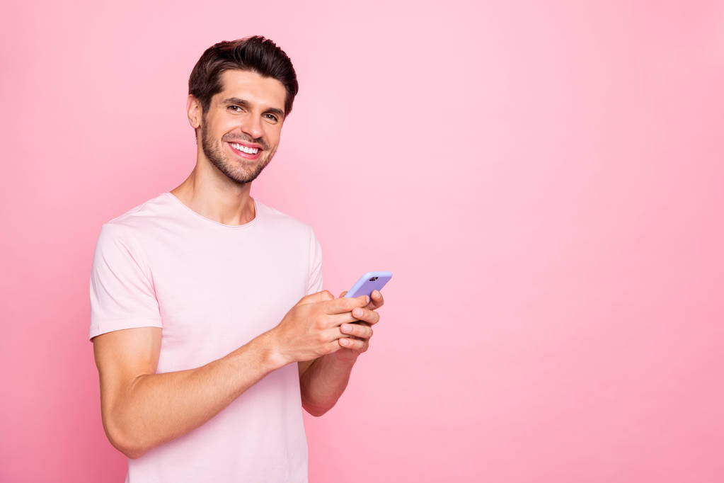 Portrét jeho milého půvabně atraktivní, veselý, sebevědomý člověk s obsahem, který drží v rukou zařízení s datováním služeb, které si užívám na růžových pastelových pozadí - Fotografie, Obrázek