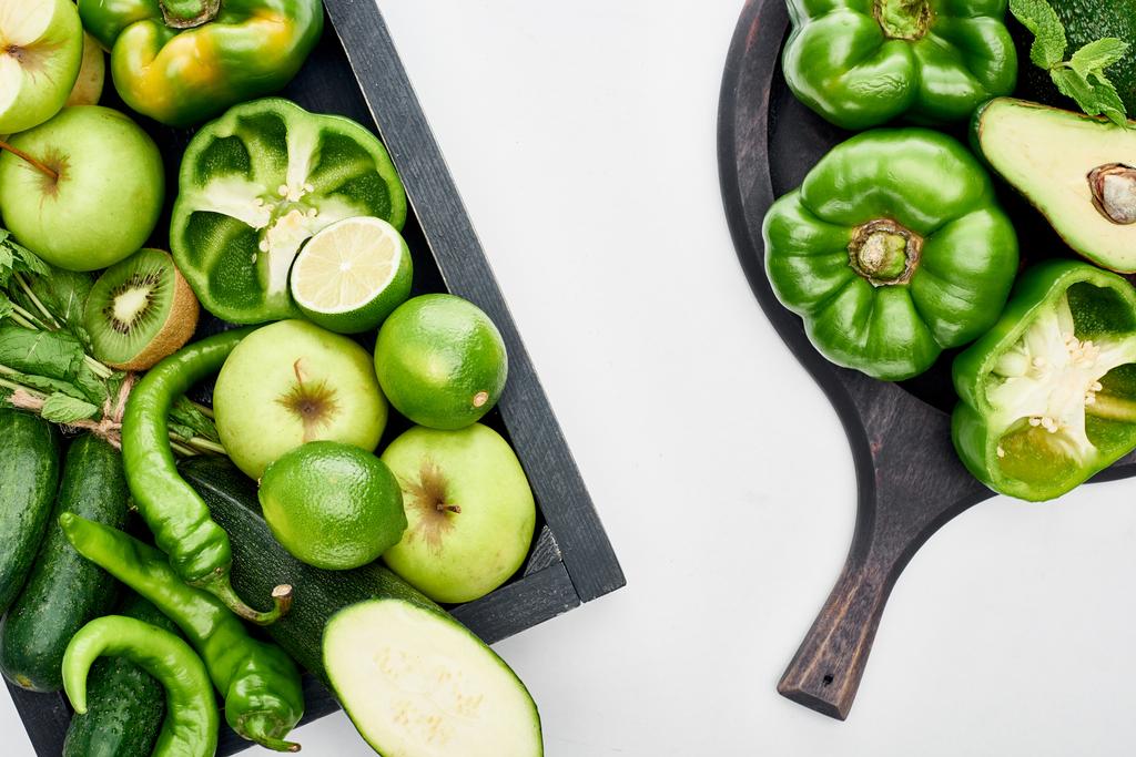 Blick von oben auf Avocado, Paprika, Kiwi, Äpfel, Limetten, Zucchini und Grün auf Pizza-Pfanne und Schachtel  - Foto, Bild