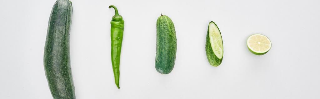 panoramische foto van verse limoen, peper, gesneden komkommers en courgette - Foto, afbeelding