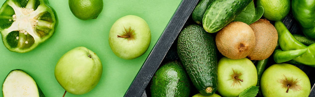 panoramic shot of apples, peppers, kiwi, greenery, limes, avocados in wooden box - Photo, Image