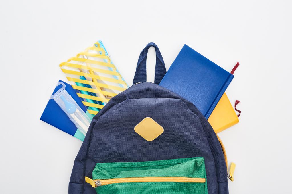 Bolsa de escola azul com diferentes materiais escolares isolados em branco
 - Foto, Imagem
