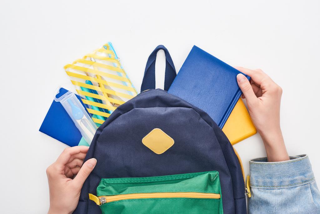 Bolsa escolar azul com bloco de notas e estojo de lápis em mãos de estudante isolada em branco
 - Foto, Imagem