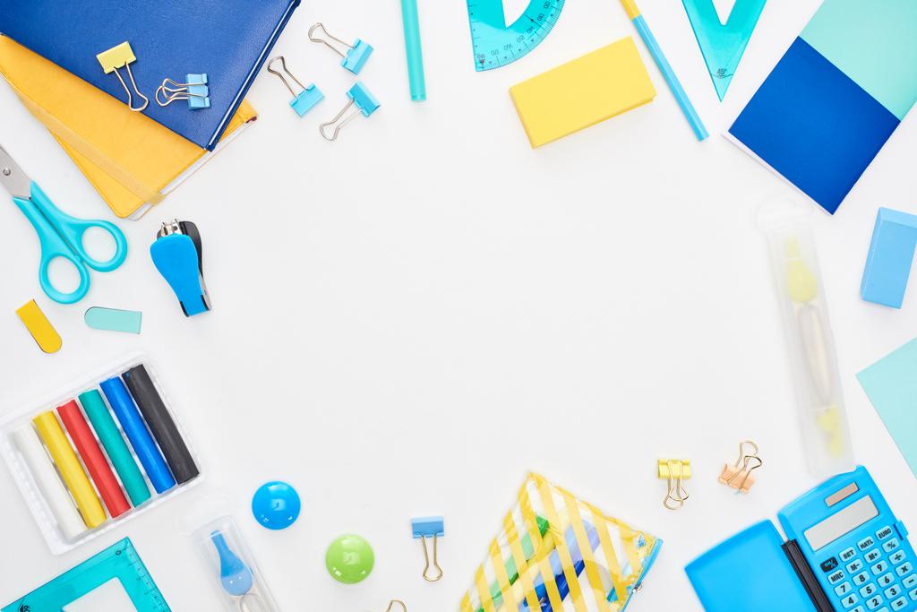 Top view of blue and yellow scattered school supplies isolated on white - Photo, Image