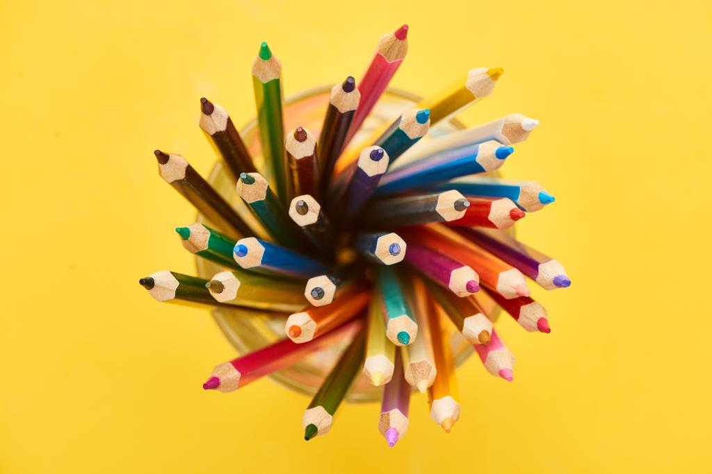 Κορυφαία θέα από ακονισμένα και φωτεινά χρωματιστά μολύβια που απομονώνονται σε κίτρινο - Φωτογραφία, εικόνα