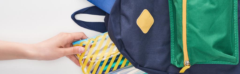 Μαθήτρια λαμβάνοντας κίτρινο μολύβι θήκη από το μπλε σχολική τσάντα απομονώθηκε σε λευκό - Φωτογραφία, εικόνα