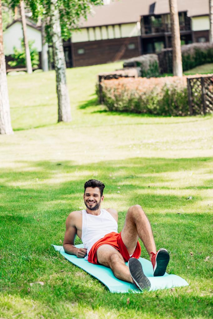 gelukkige sportman liggend op fitness man in Park  - Foto, afbeelding