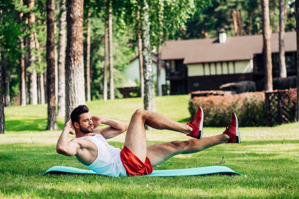 бородатый спортсмен работает на тренажерном коврике в парке
  - Фото, изображение