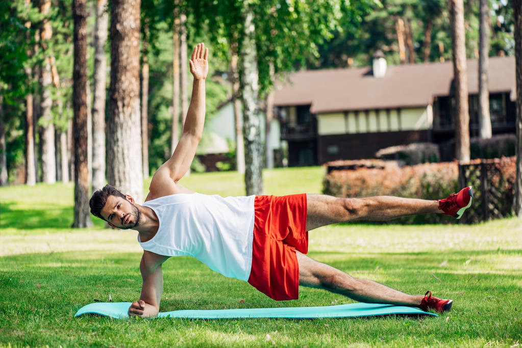 barbudo hombre deportivo haciendo ejercicio en la alfombra de fitness y hierba
  - Foto, Imagen