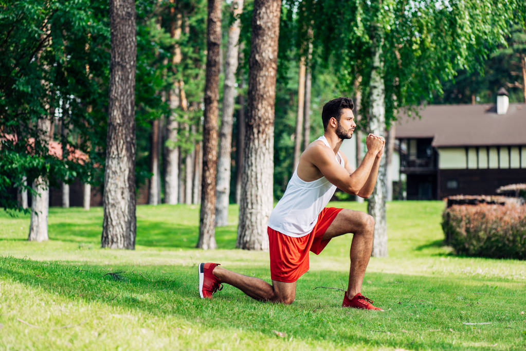 przystojny Athletic Man szkolenia w pobliżu drzew w parku  - Zdjęcie, obraz