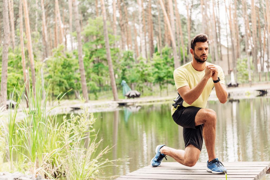 deportista atlético en ropa deportiva haciendo ejercicio cerca del lago en el bosque
  - Foto, imagen