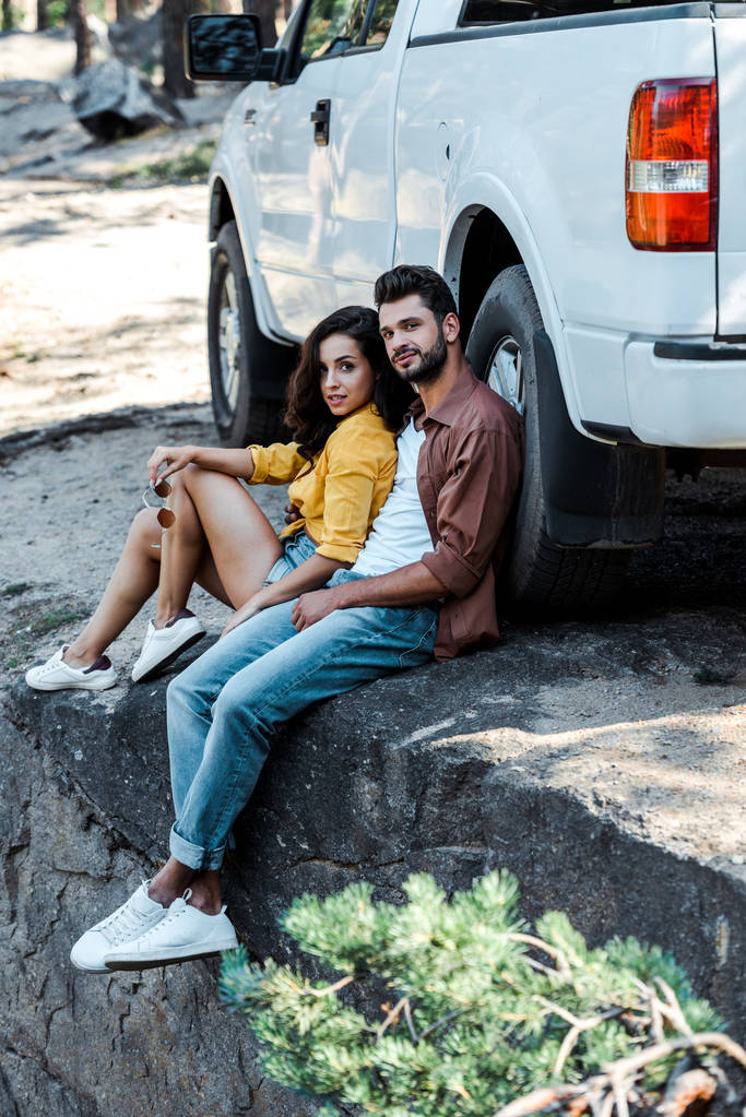 handsome and bearded man sitting near car with attractive woman  - Photo, Image