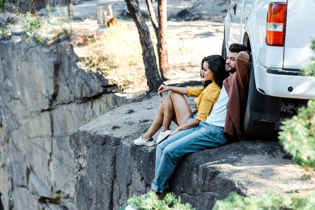 вибірковий фокус красивого чоловіка і привабливої дівчини, що сидить біля машини
  - Фото, зображення