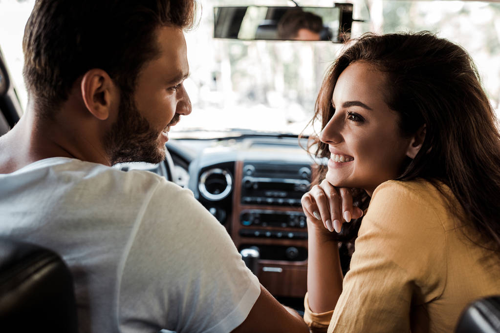 vue de côté de l'homme heureux regardant femme gaie dans la voiture
  - Photo, image
