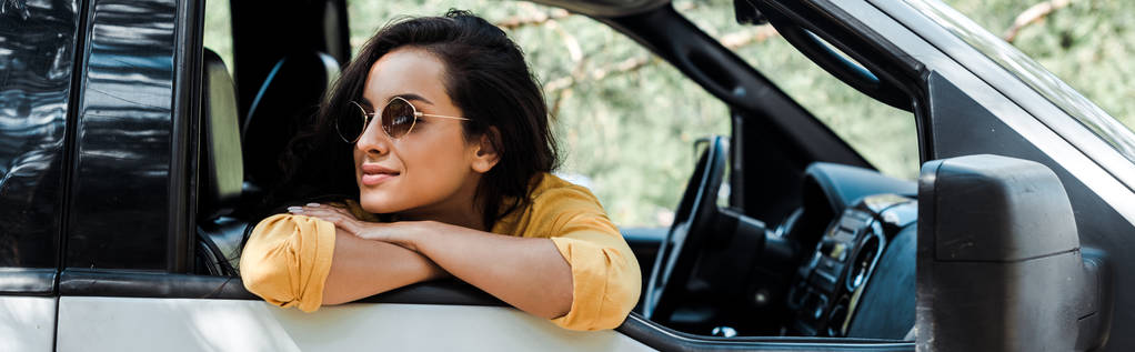 πανοραμικό σφηνάκι κορίτσι στα γυαλιά ηλίου χαμογελώντας από το παράθυρο του αυτοκινήτου  - Φωτογραφία, εικόνα