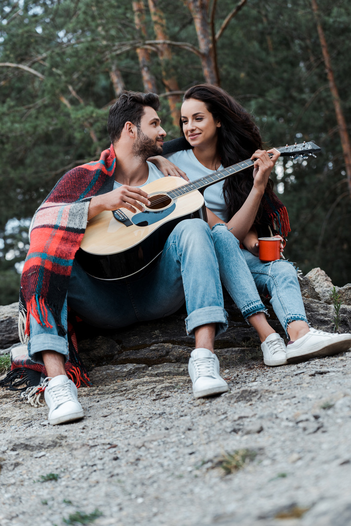 селективное внимание счастливого человека, играющего на акустической гитаре рядом с девушкой
  - Фото, изображение