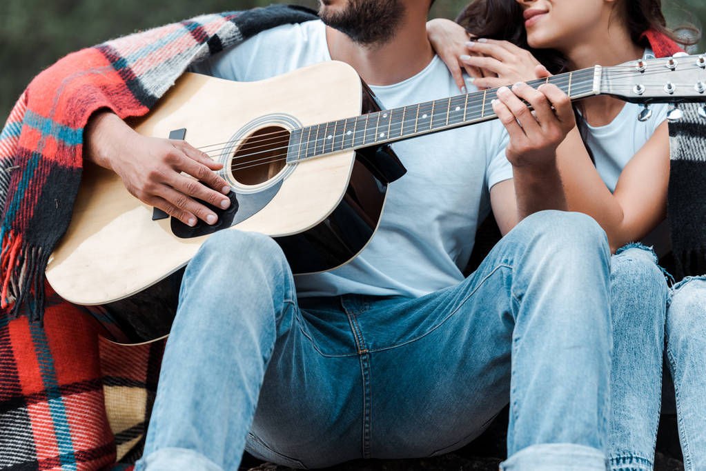 rajattu näkymä mies pelaa akustista kitaraa lähellä onnellinen tyttö
  - Valokuva, kuva