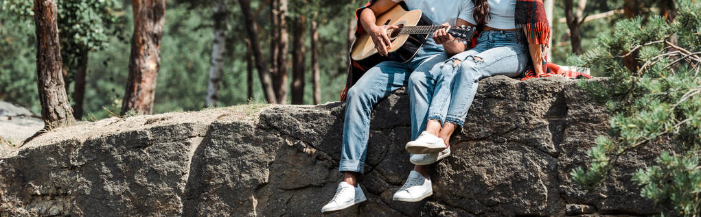 panoramiczny strzał człowieka gra na gitarze akustycznej w pobliżu kobiety w lesie  - Zdjęcie, obraz