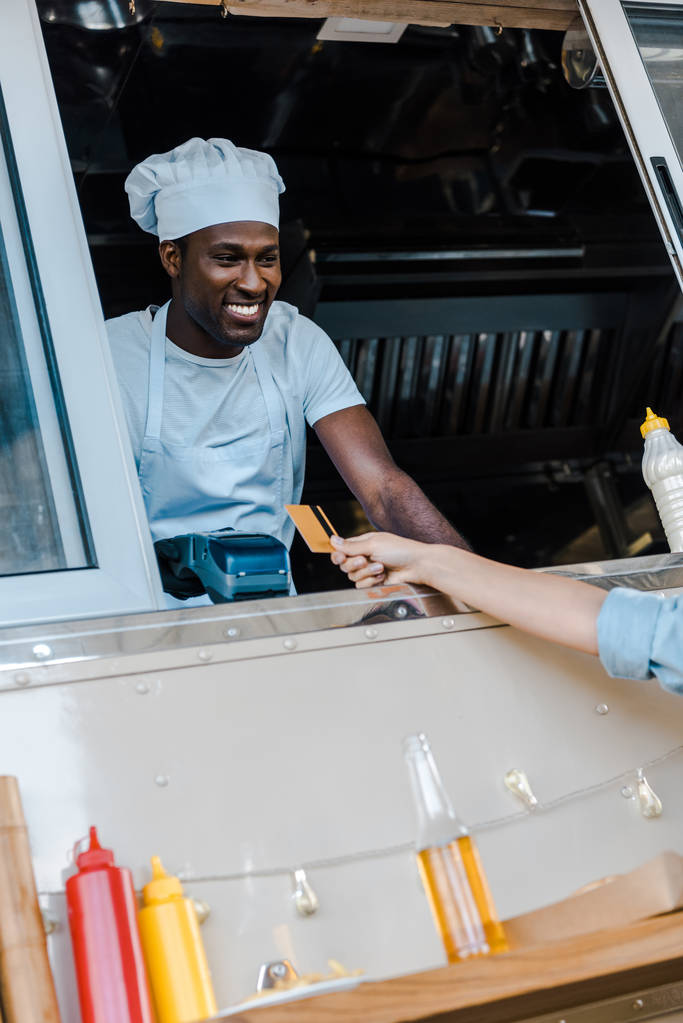 nyírt kilátás a nő, aki rendelkezik hitelkártyával fizet az élelmiszer-teherautó közelében African American Man  - Fotó, kép
