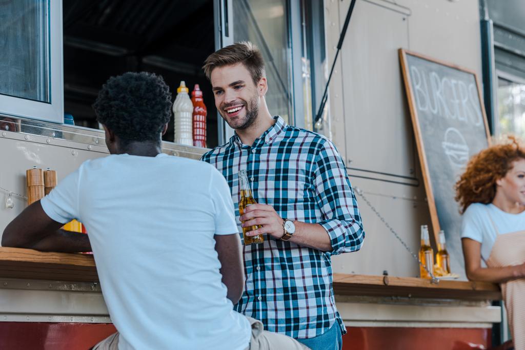 селективное внимание красивого мужчины, смотрящего на африканского американского друга и держащего пиво
  - Фото, изображение