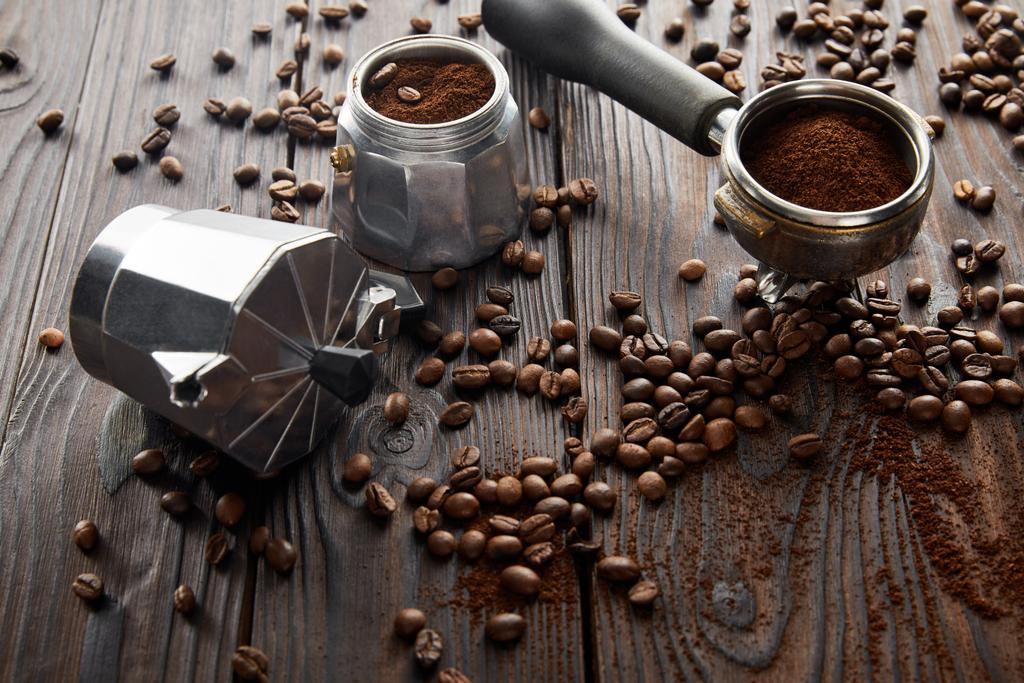 Geyser kávovar v blízkosti portafilter na dřevěné ploše s kávovými fazolemi - Fotografie, Obrázek