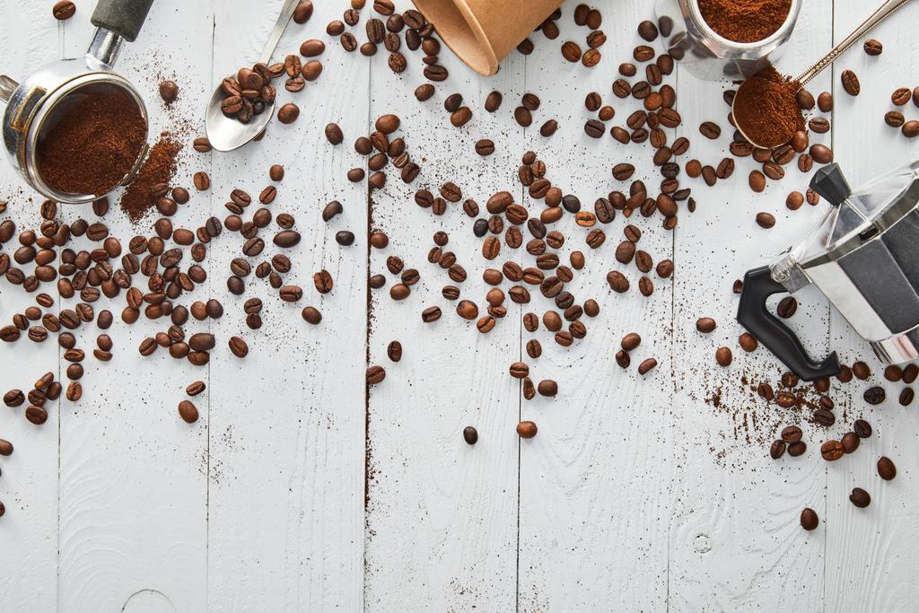 Pohled na gejzír kávovaru, portafiltr, lžíce a papírový pohár na bílém dřevěném povrchu s kávovými fazolemi - Fotografie, Obrázek