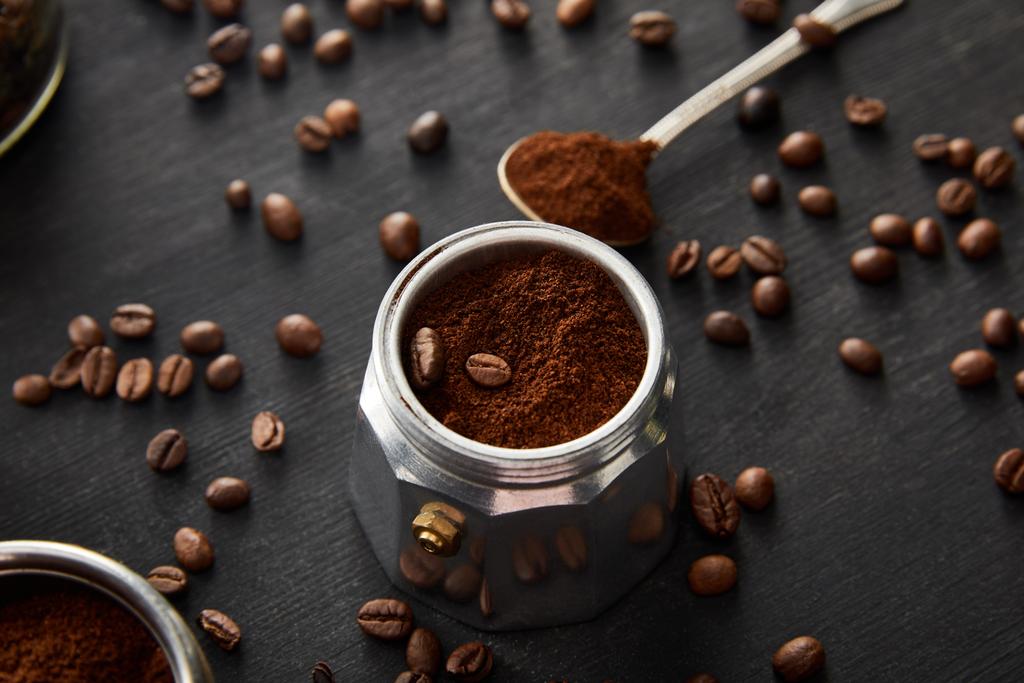 Část gejzíru kávy se mleté kávou blízko lžíce na tmavém dřevěném povrchu s kávovými fazolemi - Fotografie, Obrázek