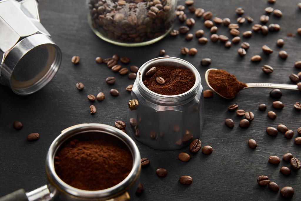 Části gejzíru kávy v blízkosti lžičky s kávou a portafiltrem na tmavém dřevěném povrchu s kávovými fazolemi - Fotografie, Obrázek