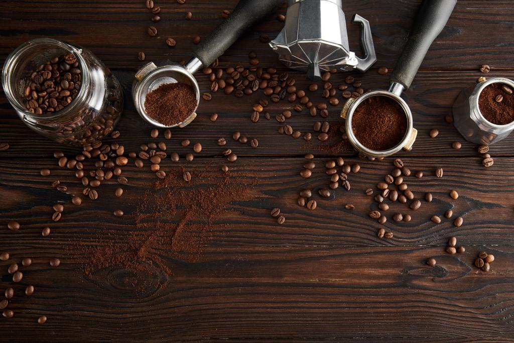 コーヒー豆と暗い木製の表面に間欠泉のコーヒーメーカーとポルタフィルターの近くのガラス瓶のトップビュー - 写真・画像