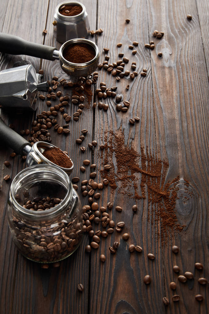 Dark wooden surface with glass jar, portafilters, geyser coffee maker and coffee beans - Photo, Image