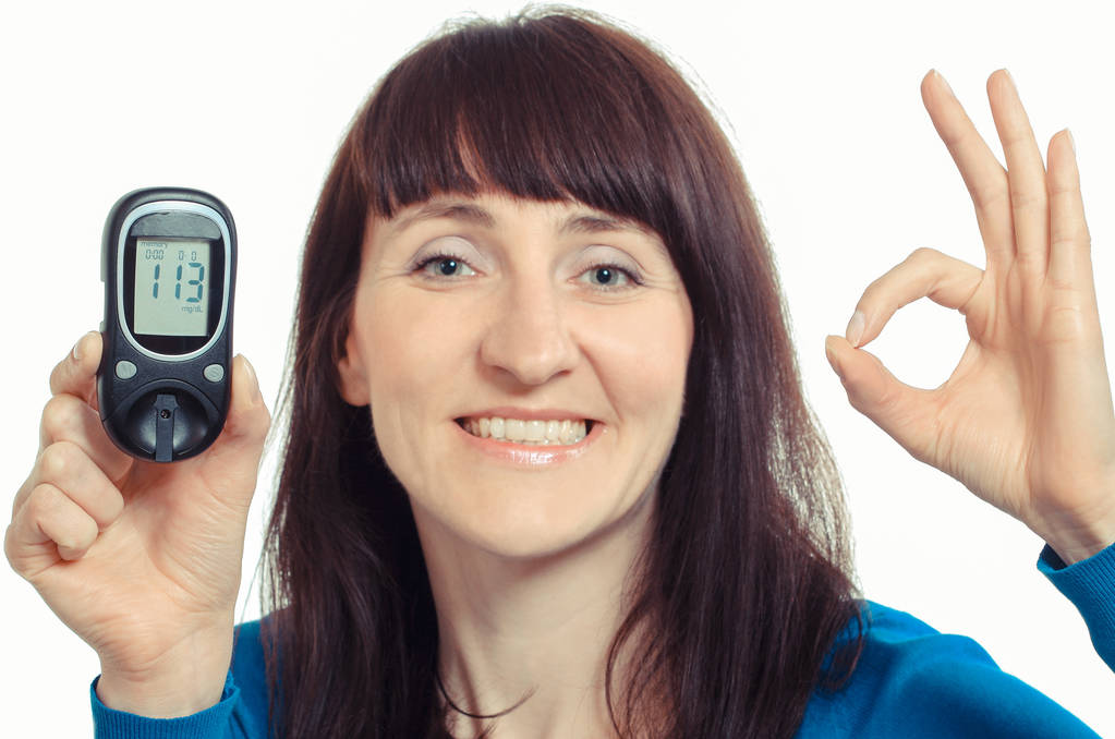 Mujer sonriente con medidor de glucosa mostrando signo ok. Control del nivel de azúcar
 - Foto, imagen