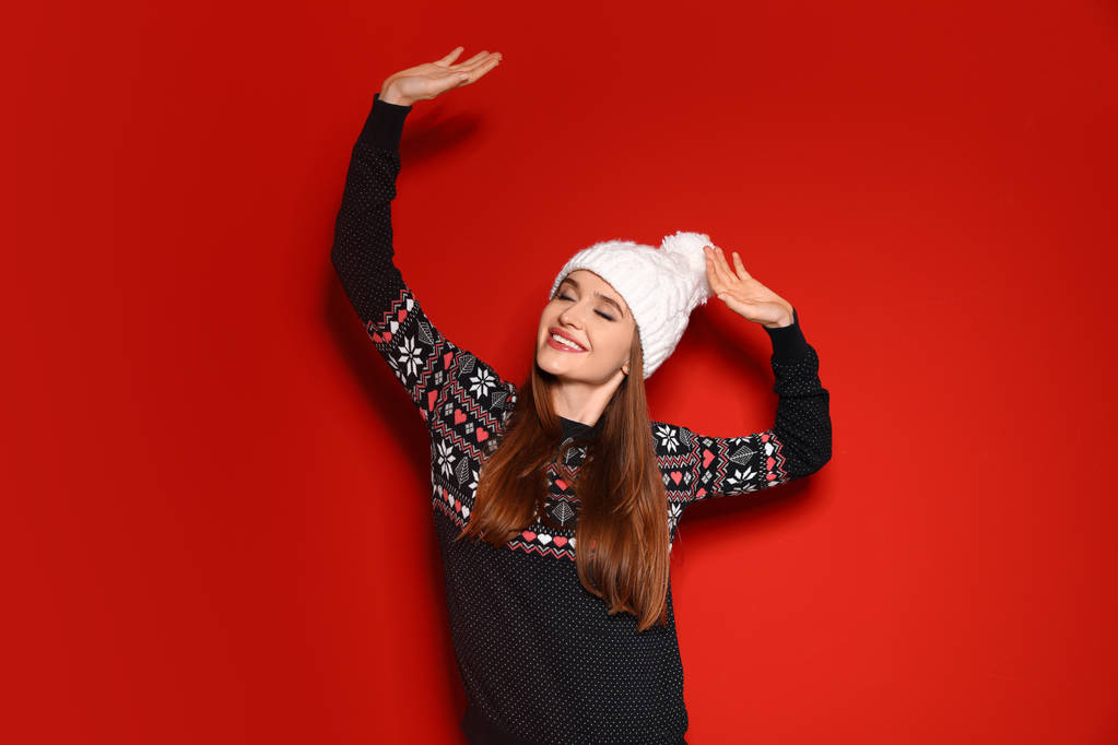 Молода жінка в новорічному светрі на червоному тлі
 - Фото, зображення